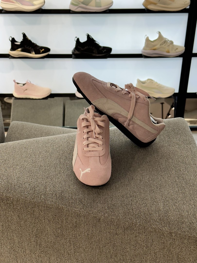 A pair of pink Puma sneakers displayed on a textured gray surface.
