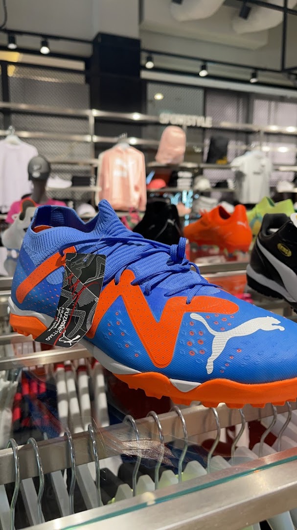 A close-up of a blue and orange Puma soccer cleat with a tag attached.