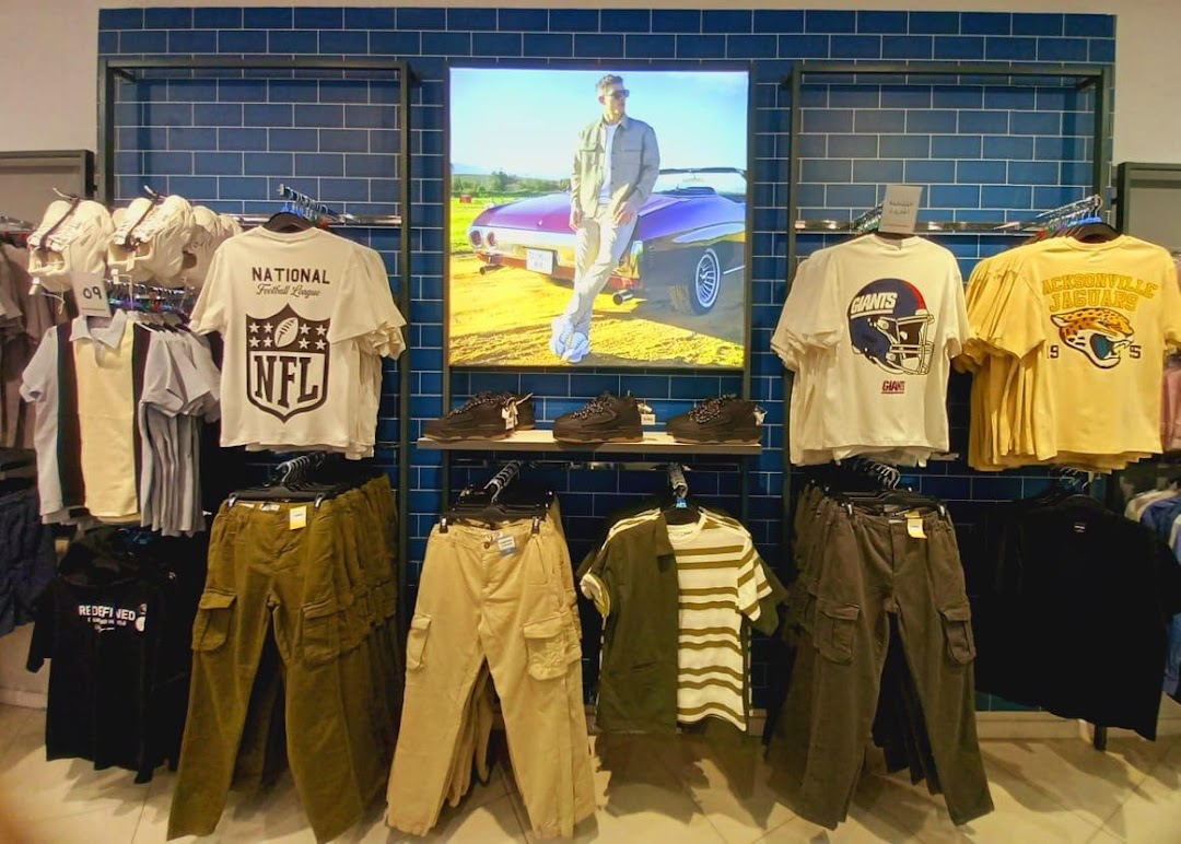 A display of casual men's clothing, including t-shirts and cargo pants, with a lifestyle image.