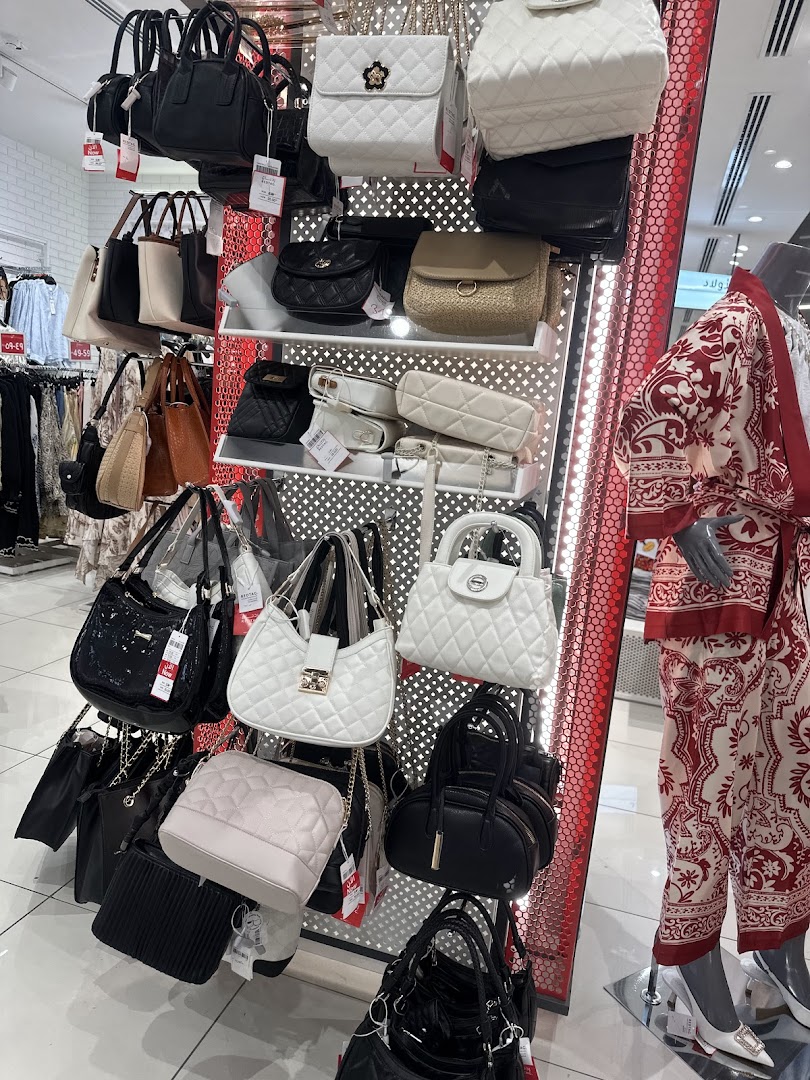 A display of various handbags in different styles and colors, including quilted and patent leather.