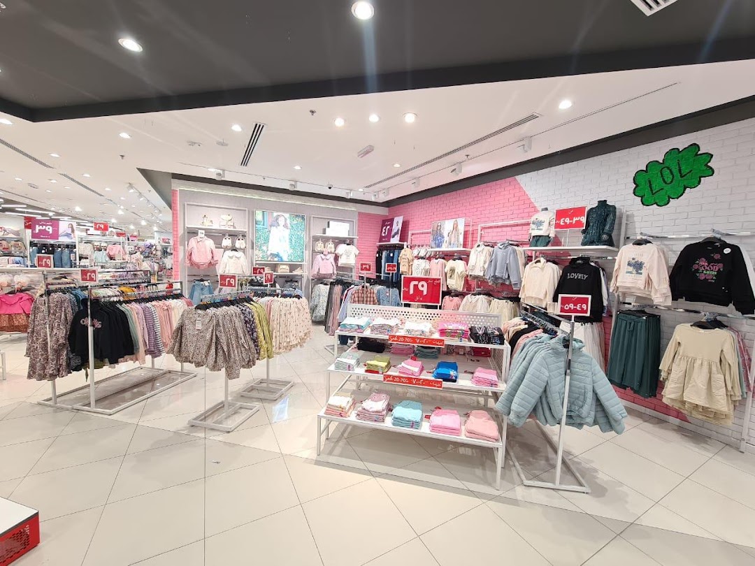 Interior view of a brightly lit clothing store with racks of colorful apparel for children.