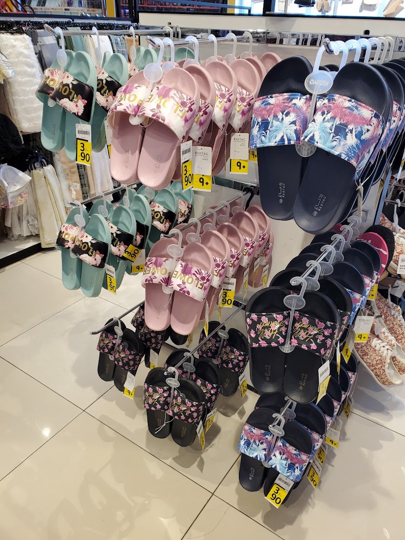 A display of colorful slide sandals with floral and tropical prints on hangers.