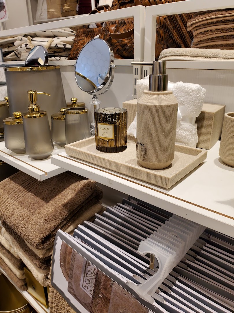 A display of bathroom accessories including soap dispensers, a mirror, candle, and towels.