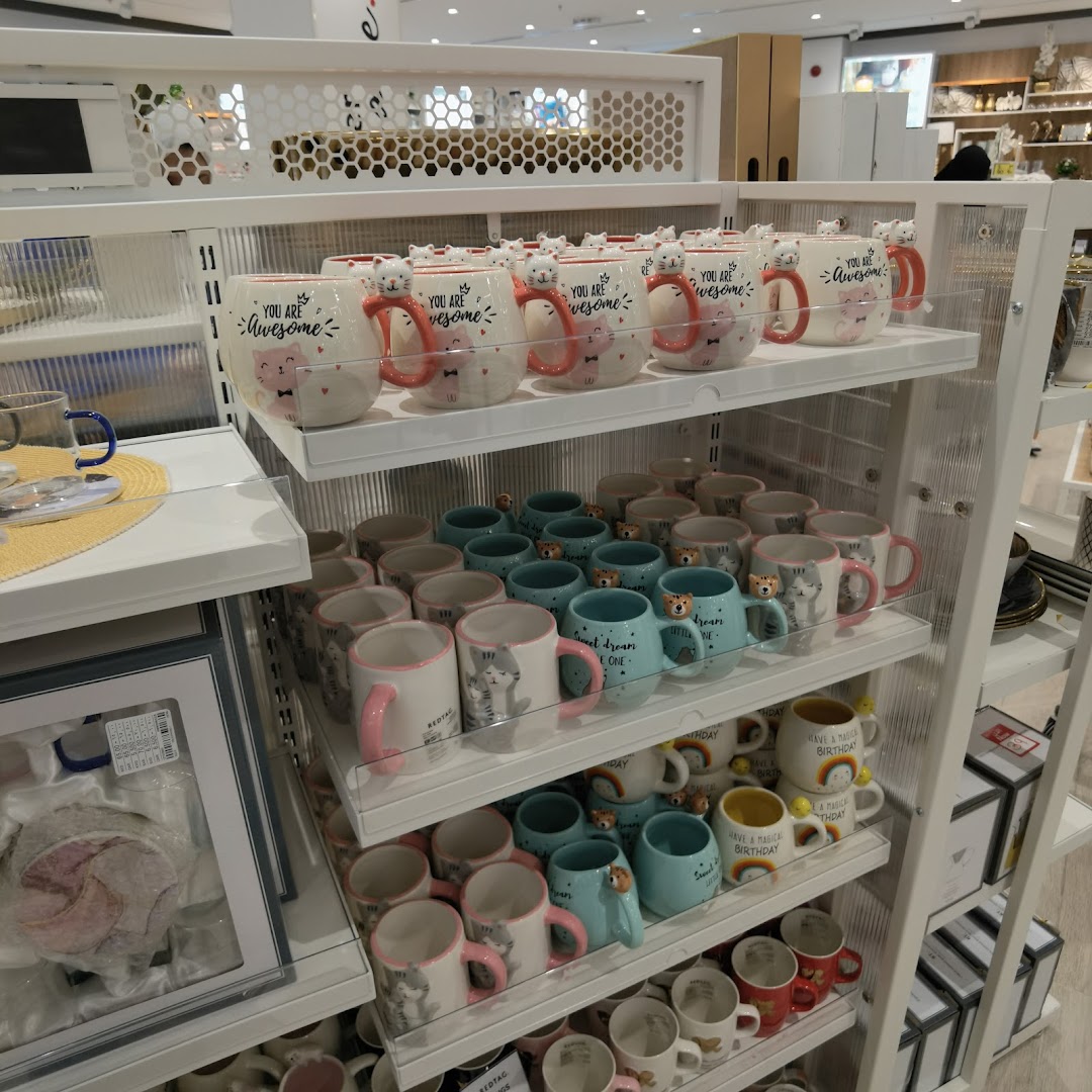 Shelves filled with various cute mugs featuring cat designs and positive affirmations.