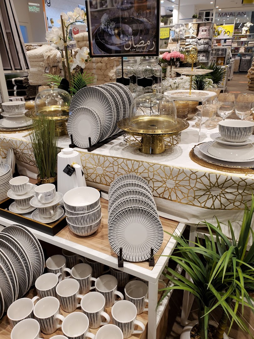 A display of elegant tableware, including plates, bowls, and cups, with a Ramadan-themed sign.