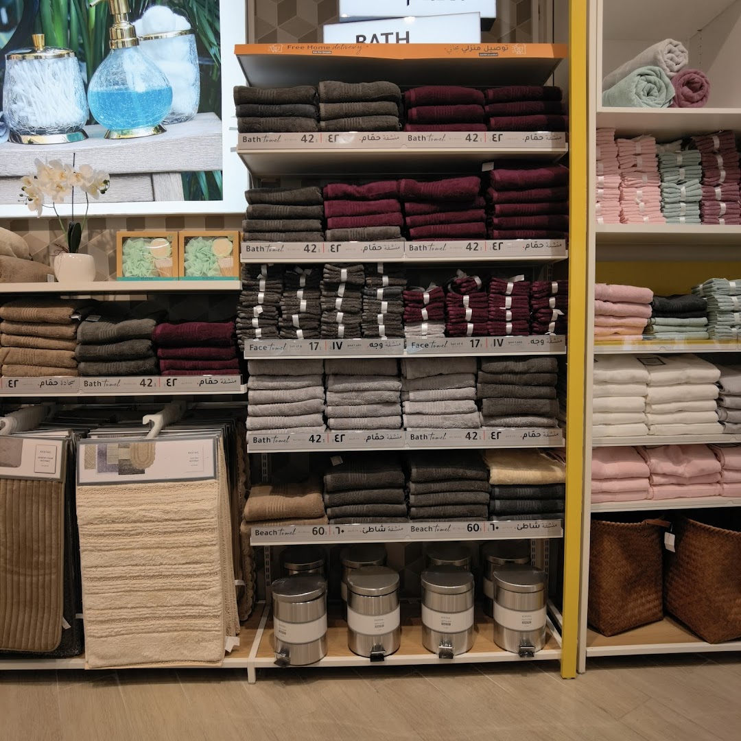 Shelves stocked with various towels, bath mats, and bathroom accessories in a retail store.