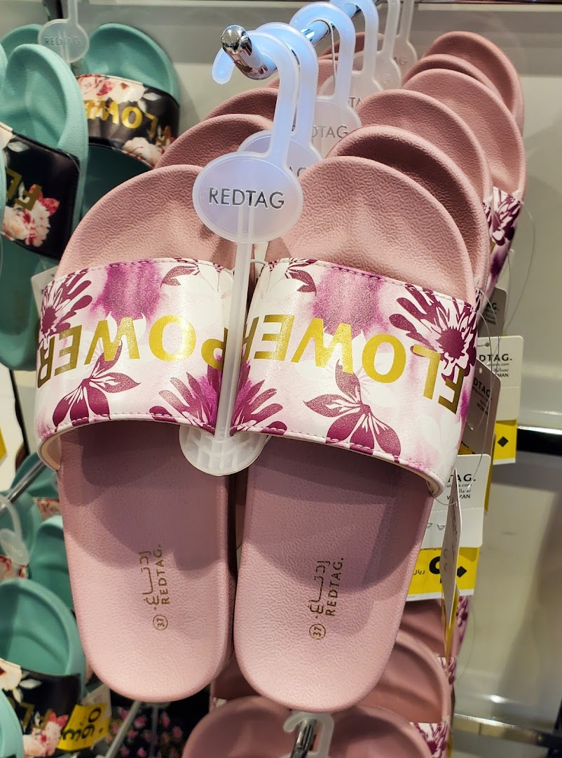 A pair of pink slide sandals with a floral pattern and the word 'POWER' in gold.