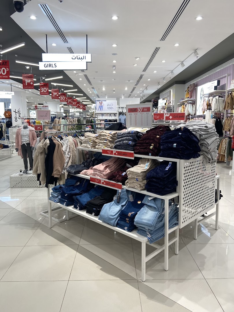 Interior view of a clothing store with racks of jeans and apparel, featuring sale signs.
