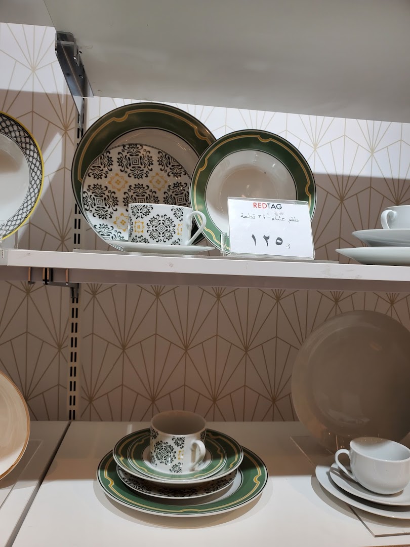 A display of dinnerware sets, including plates and cups, with price tags visible.