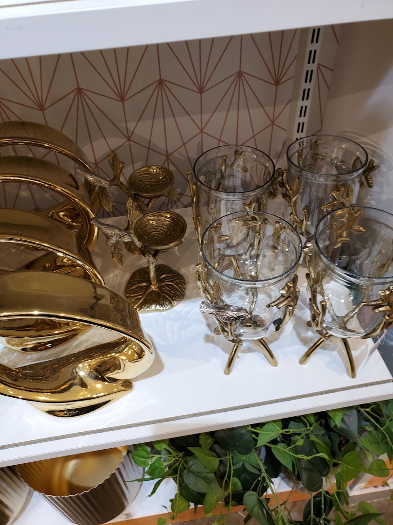 Gold decorative items including candle holders and glass vases with bird and branch accents.