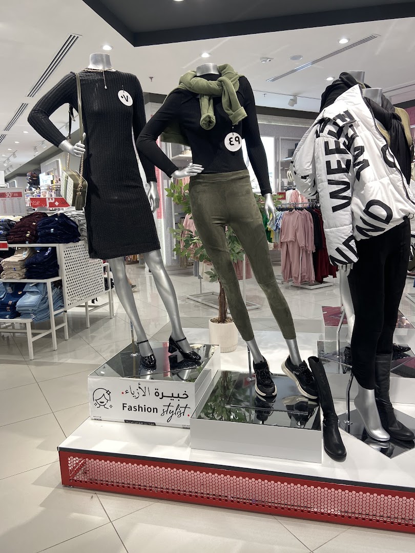 Mannequins display fashionable outfits inside a retail store, showcasing clothing and accessories.