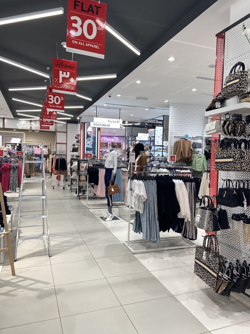 Interior view of a clothing store with apparel and accessories on display, featuring sale signs.