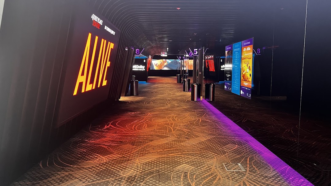A modern cinema hallway with illuminated movie posters and numbered doors.