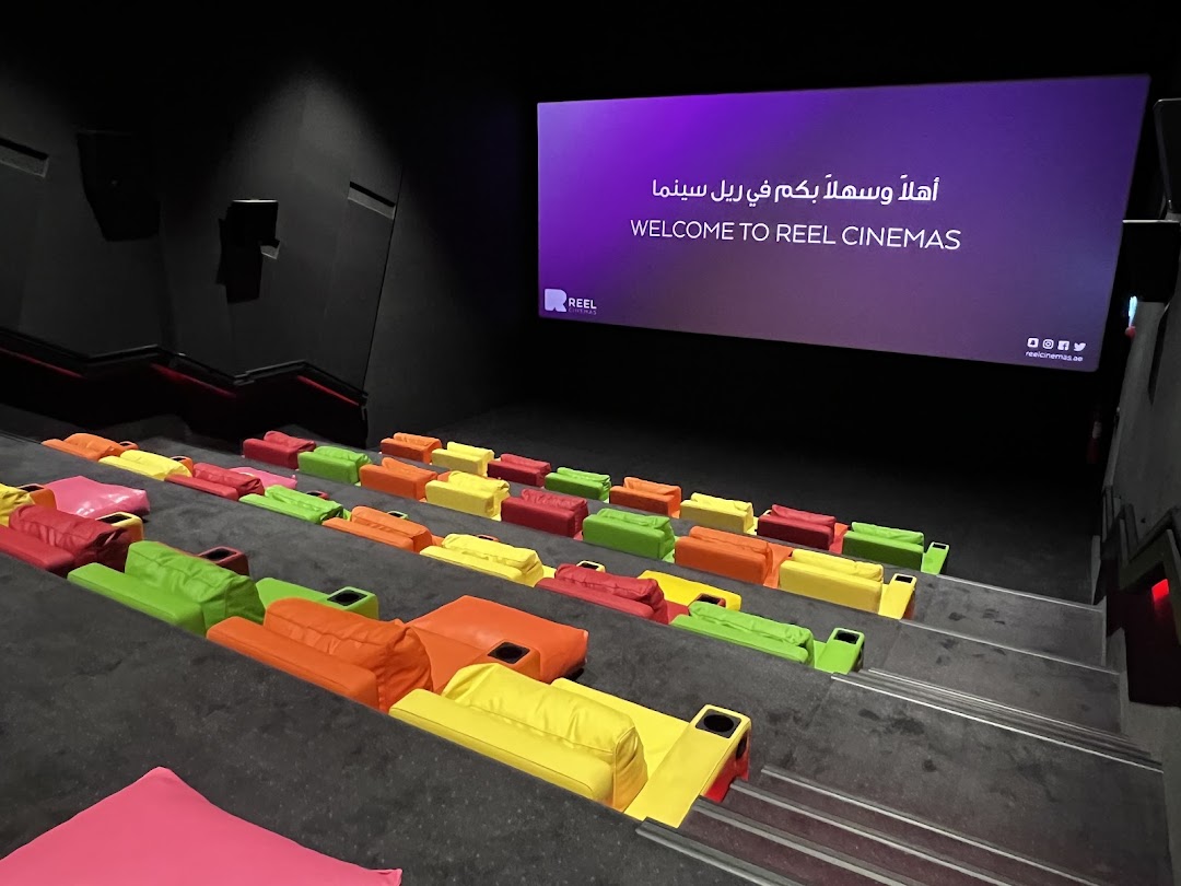 A cinema hall with colorful beanbag seats and a welcome screen.