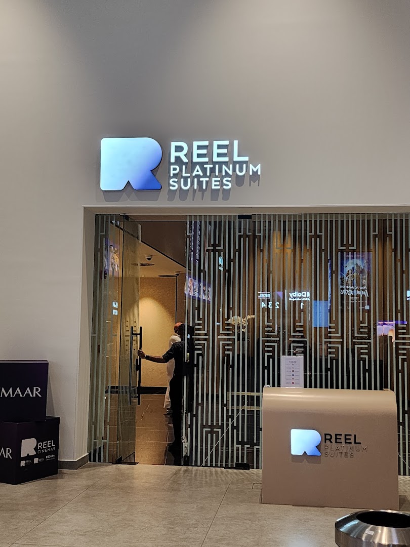 The entrance to Reel Platinum Suites cinema with a prominent illuminated logo and a person entering.