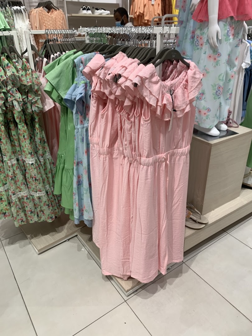A display of colorful summer dresses on hangers inside a retail store.