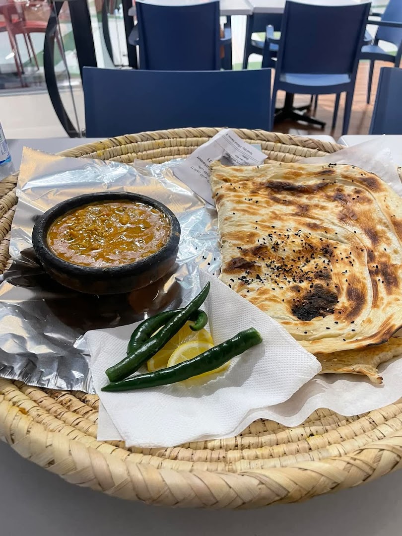 A traditional meal with a stew, flatbread, chili peppers, and lemon served in a woven basket.