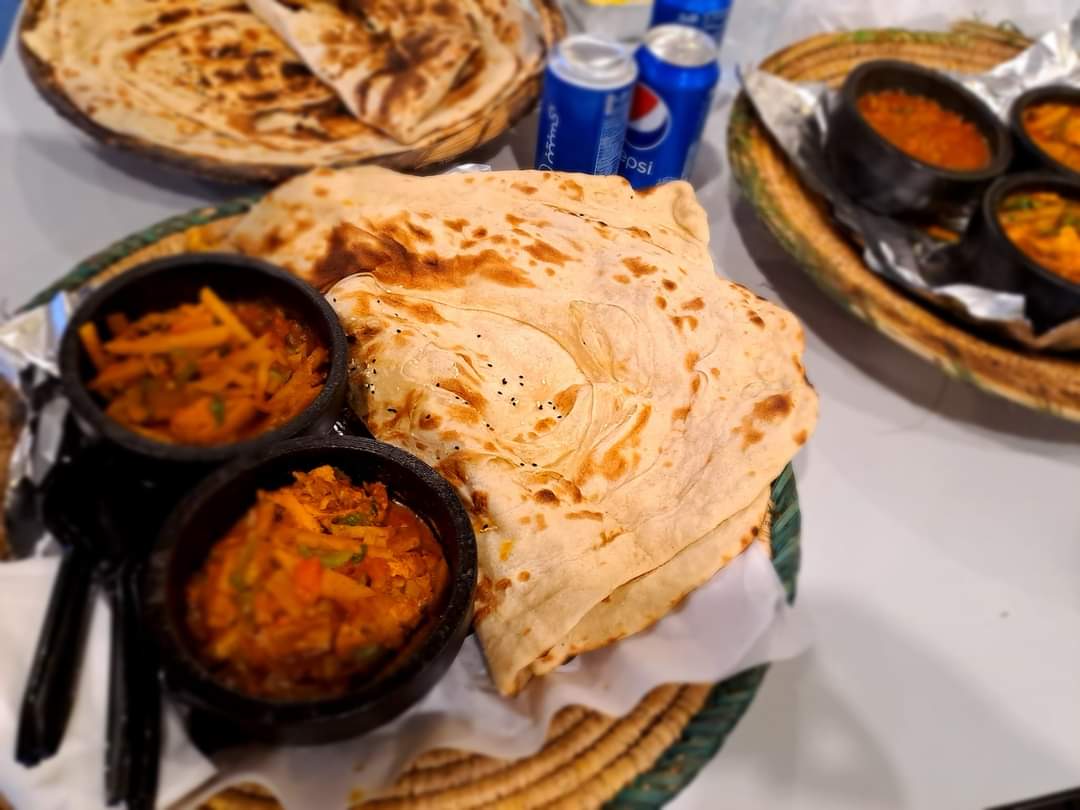 A close-up shot of delicious flatbread with savory stews and Pepsi cans.