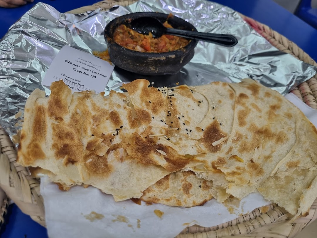 A close-up of a traditional Middle Eastern dish with flatbread and a stew served in a clay pot.
