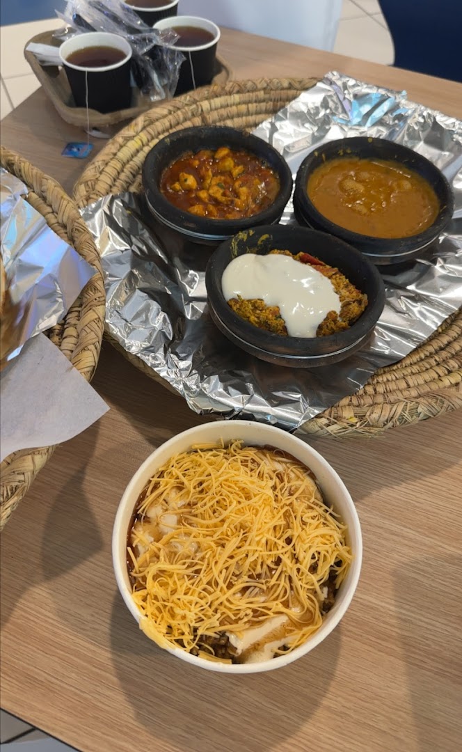 A close-up of several bowls of food and cups of tea on a wooden table.
