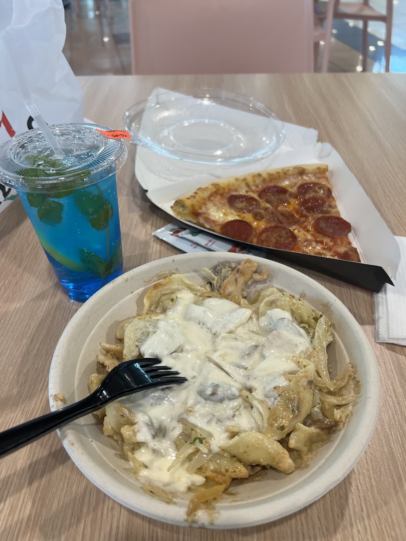 A slice of pepperoni pizza and a creamy pasta dish with a blue beverage.