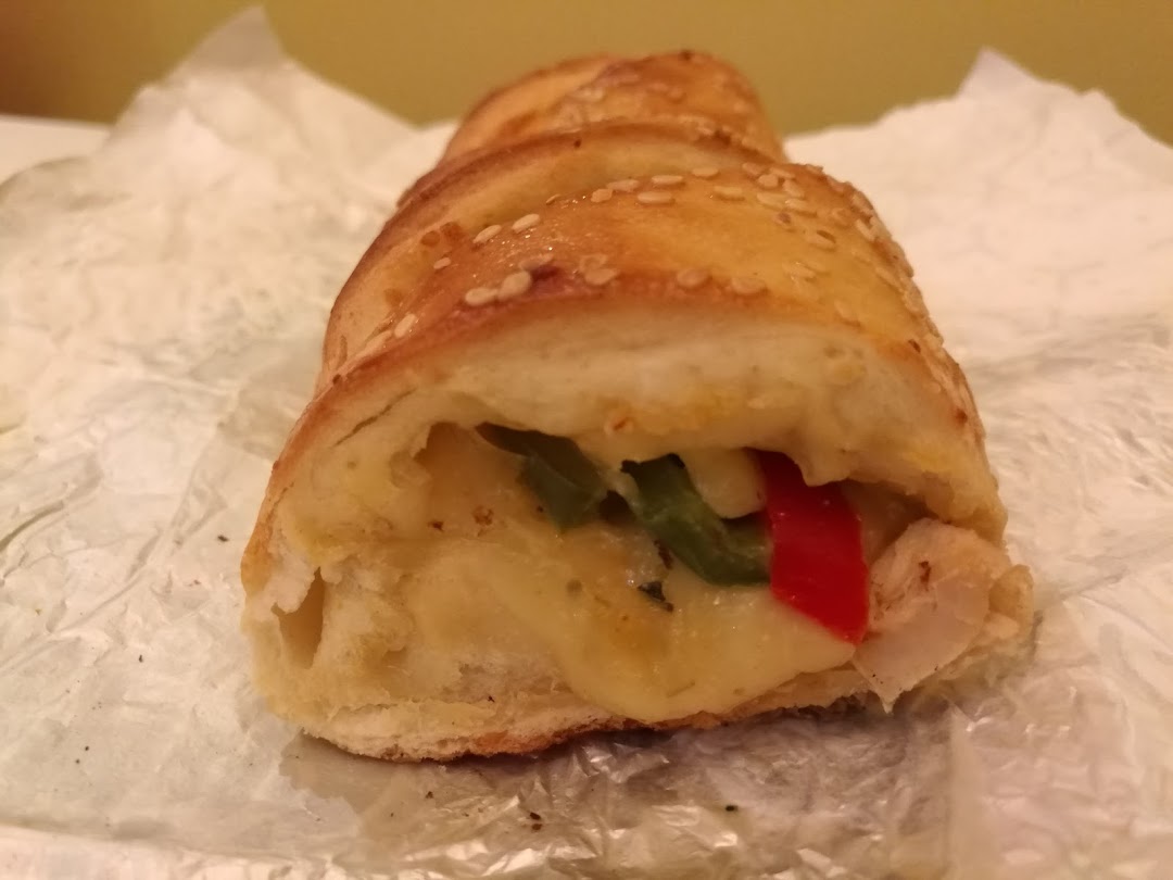 A close-up of a Sbarro stromboli filled with cheese, chicken, and peppers.