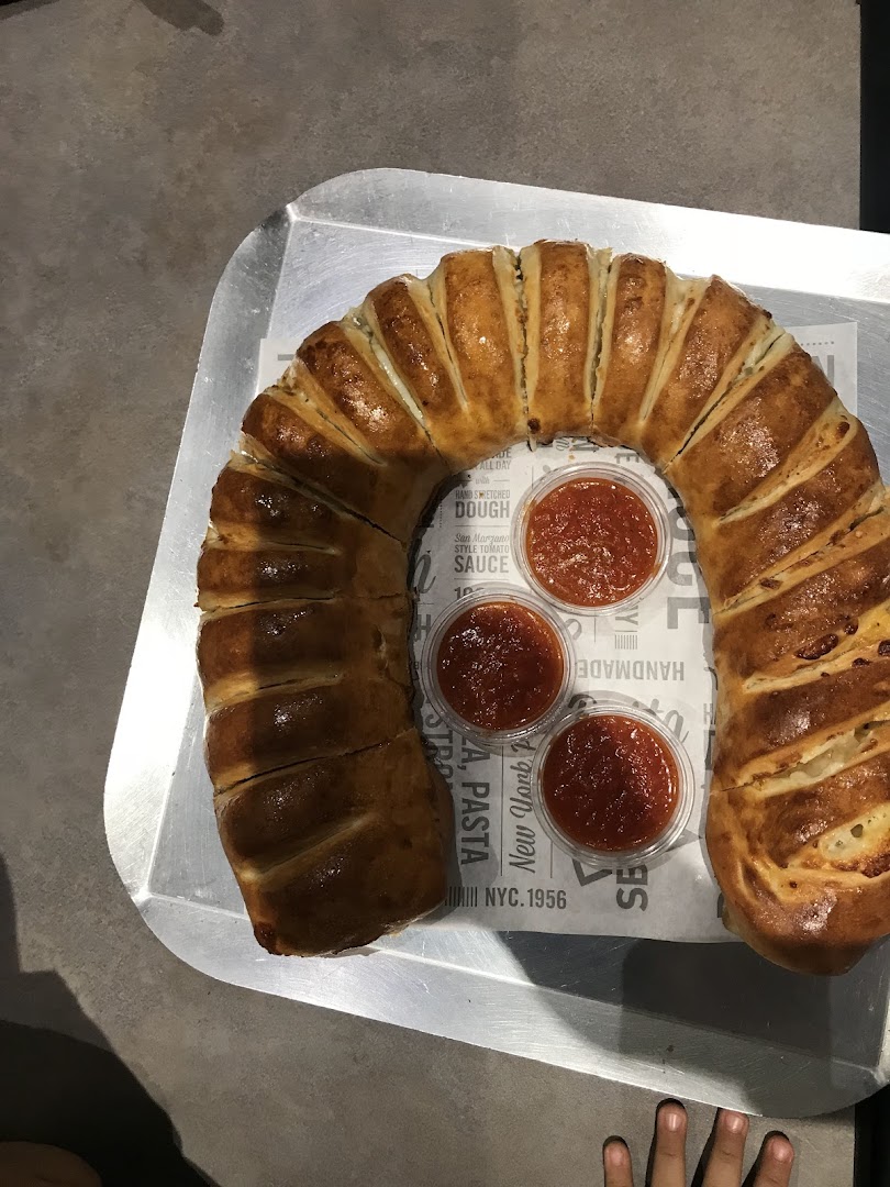 A horseshoe-shaped bread filled with cheese and served with three cups of tomato sauce.