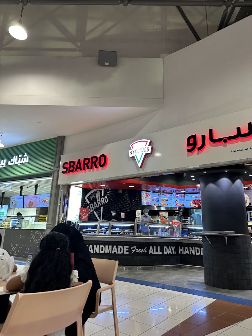A Sbarro restaurant counter with staff serving customers and food displays.