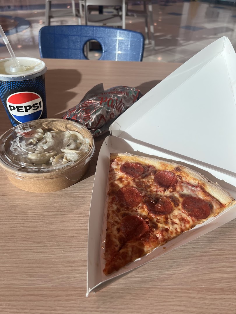 A slice of pepperoni pizza, a cup of Pepsi, and a side dish on a wooden table.