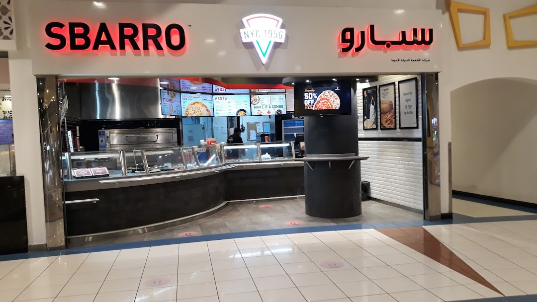 The Sbarro pizza shop front with illuminated signage and a display of food items.