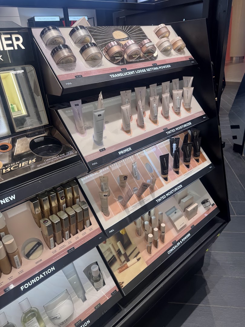 A display of various makeup products including foundations, primers, and setting powders.