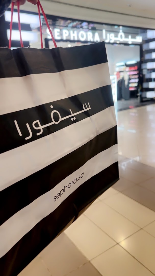 A shopping bag with Sephora branding in front of the Sephora store.