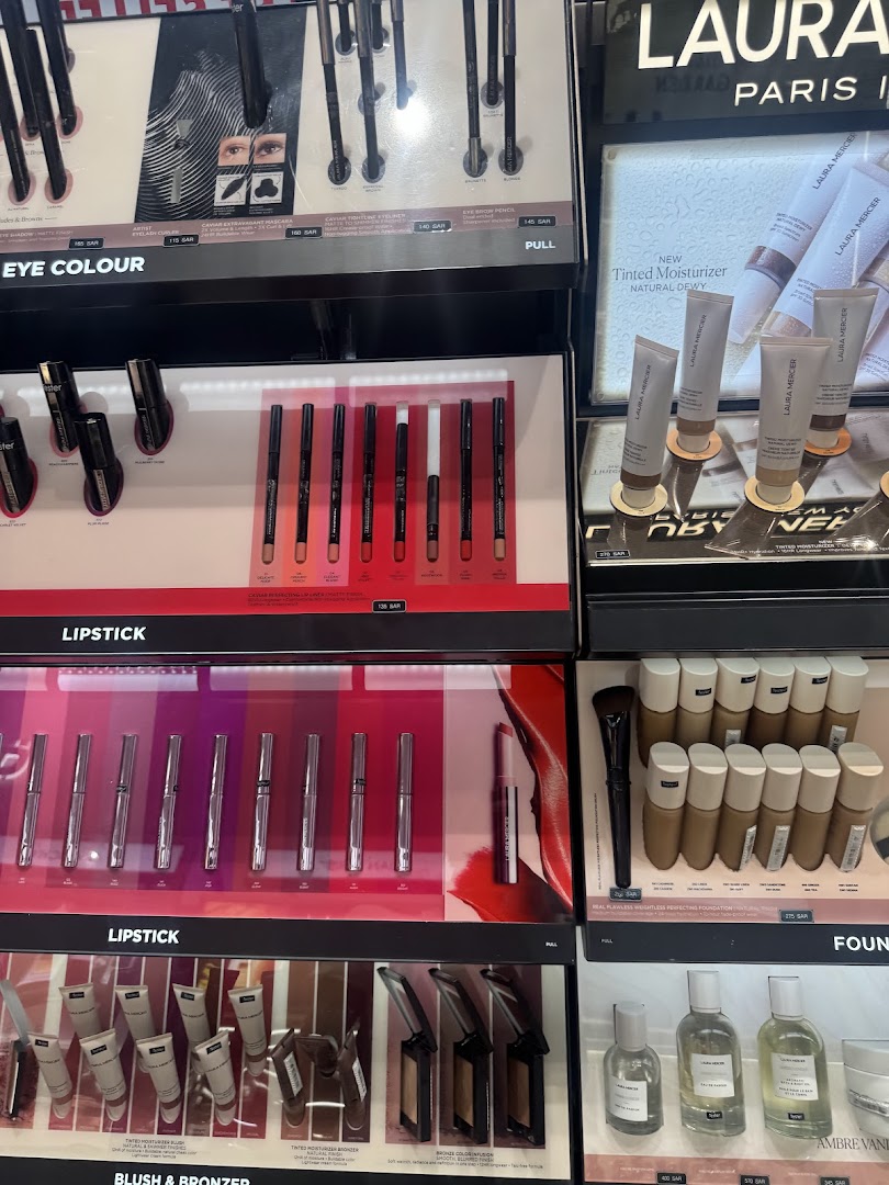 A display of various makeup products including lipsticks, eye pencils, and foundations from brands like Laura Mercier.