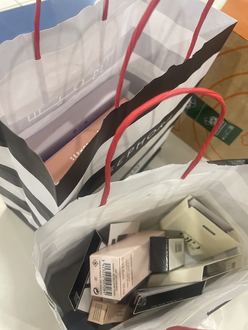 Several Sephora shopping bags filled with various beauty products and boxes.