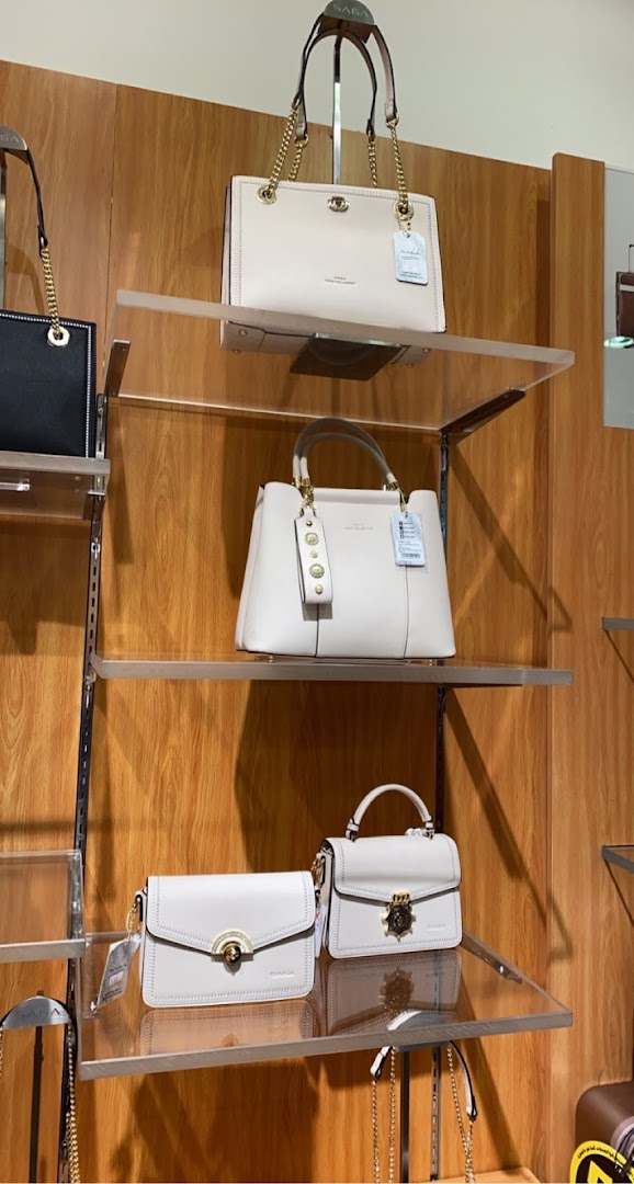 A display of elegant white handbags on shelves, showcasing the Saga brand.