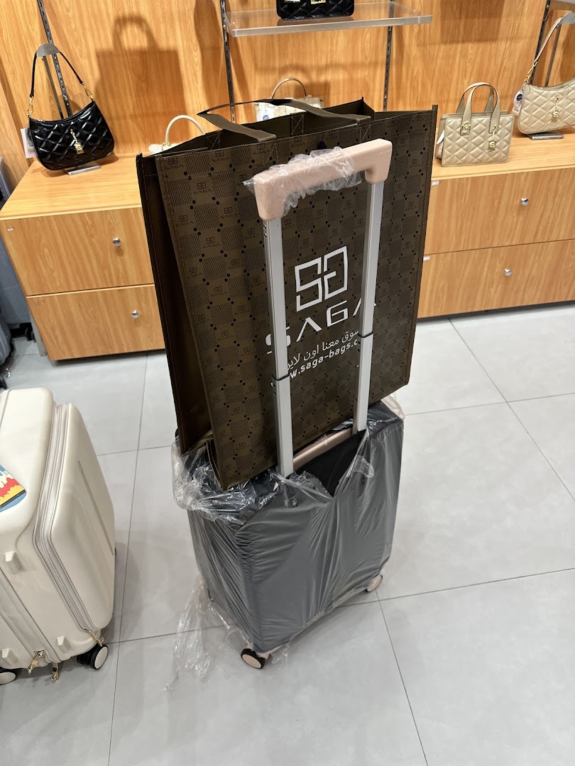 A shopping bag with the Saga logo on a suitcase, with handbags displayed in the background.