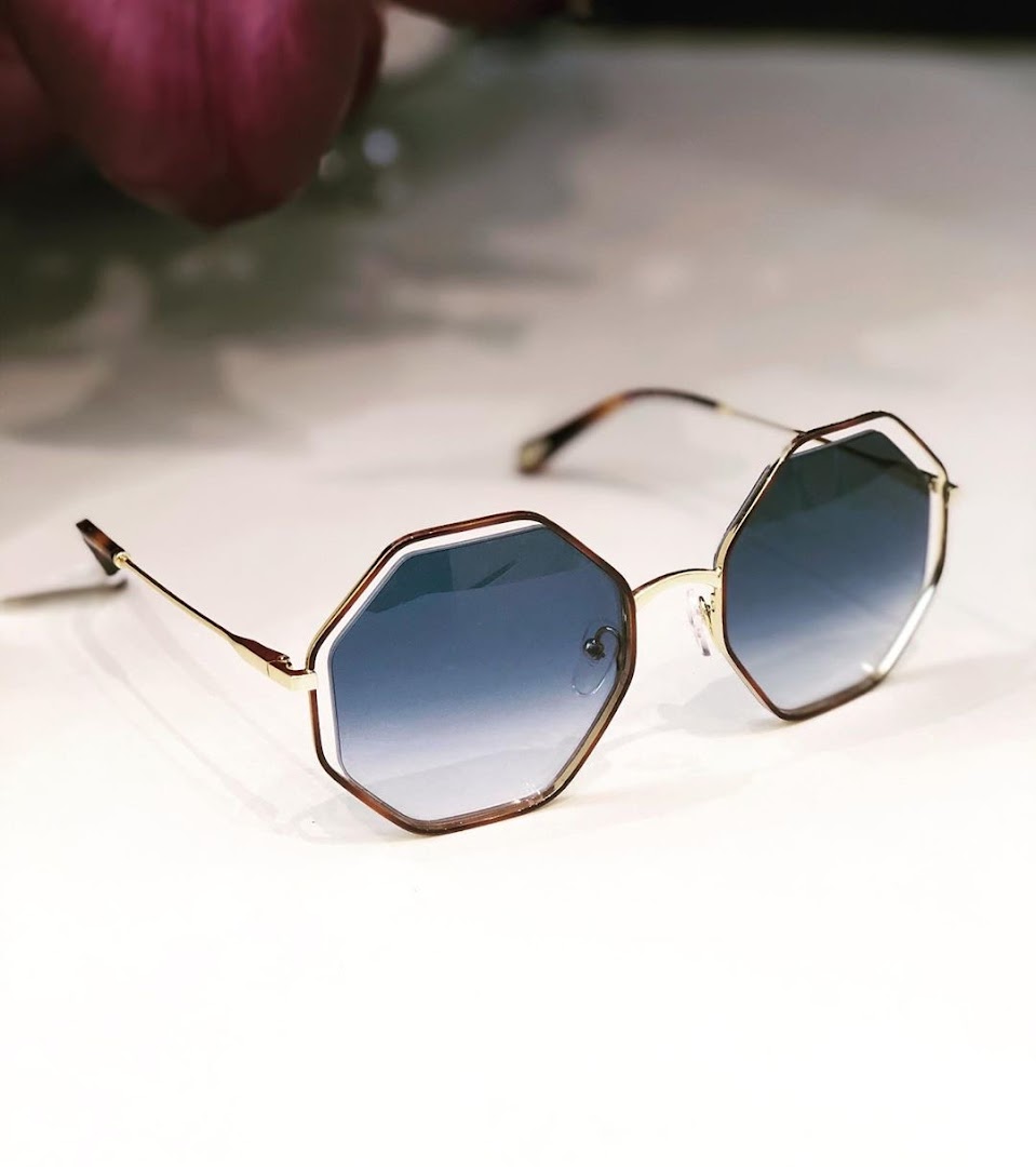 A stylish pair of octagonal sunglasses with gradient blue lenses and gold frames.
