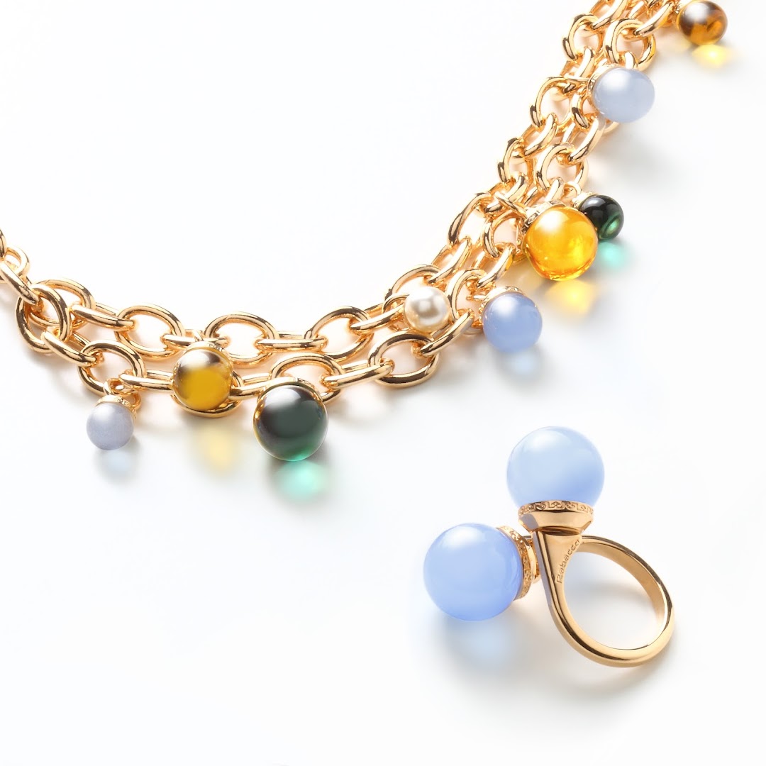 A gold necklace with colorful beads and a matching ring with blue stones.