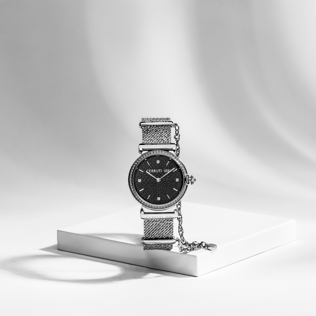 A black and white image of a women's wristwatch with a mesh band and diamond accents.