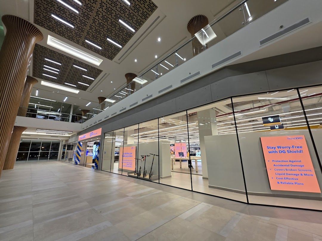 The exterior of a Sharaf DG electronics store with a large glass facade and promotional signage.