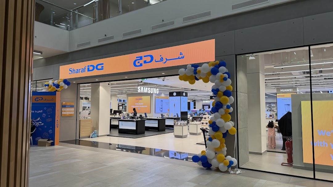 Sharaf DG electronics store entrance decorated with balloons, showcasing Samsung and Huawei displays.