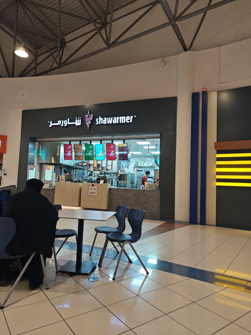 The Shawarmer shop front with seating area and a customer waiting.
