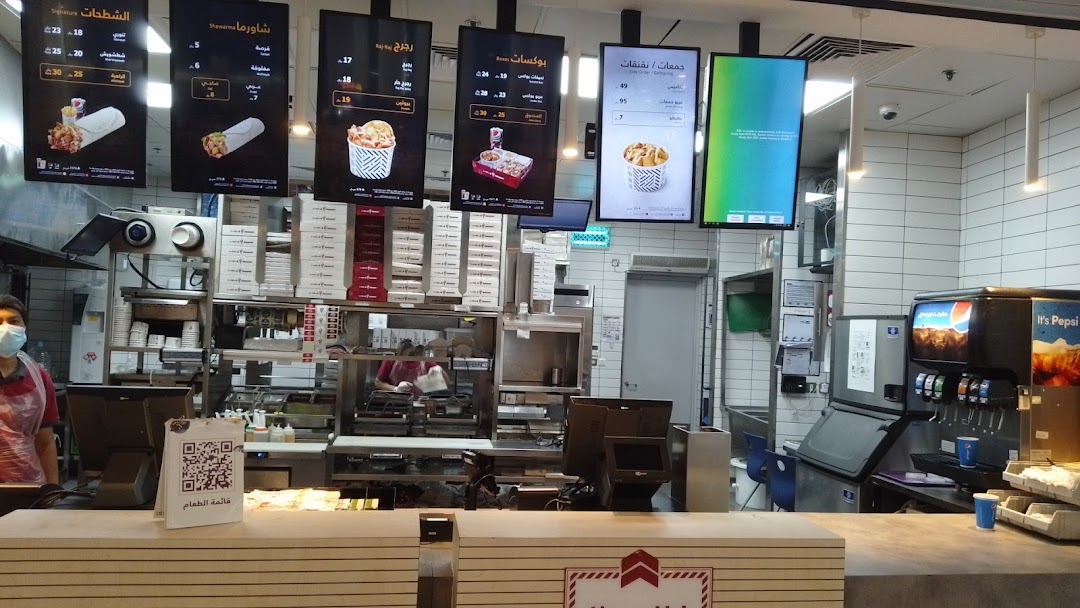 Interior view of a Shawarmer restaurant with digital menus and a service counter.