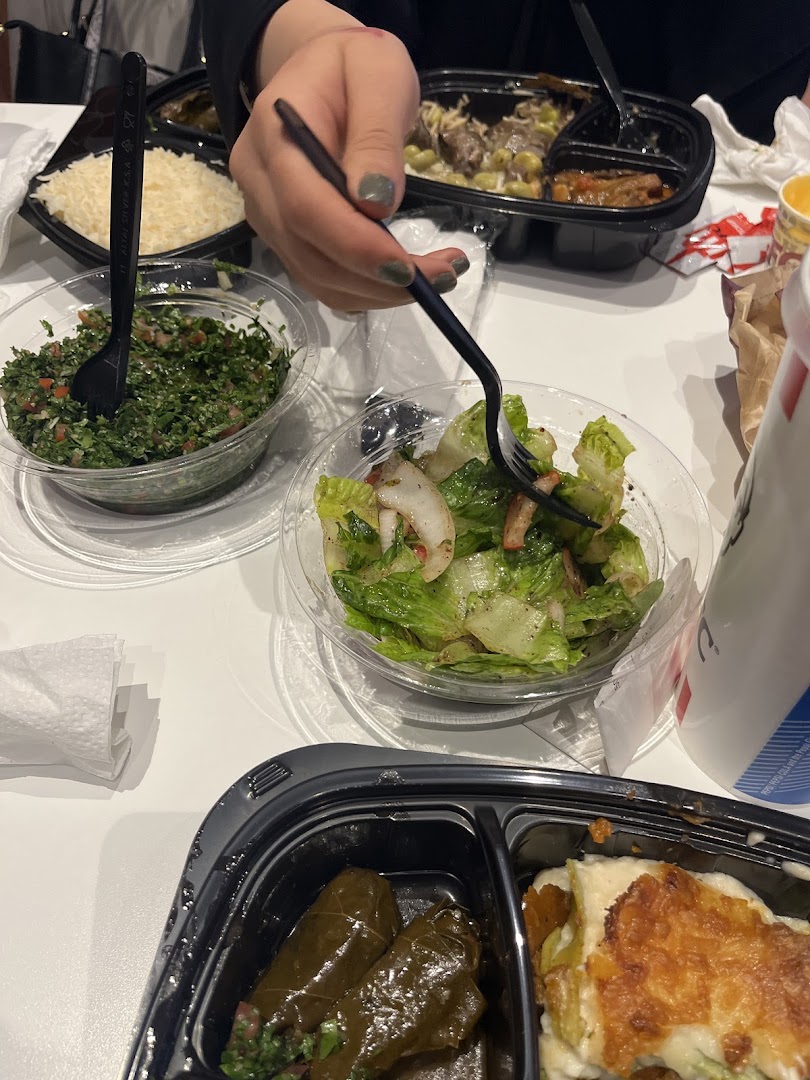 A table laden with various Lebanese dishes, including tabbouleh, salad, and stuffed grape leaves.