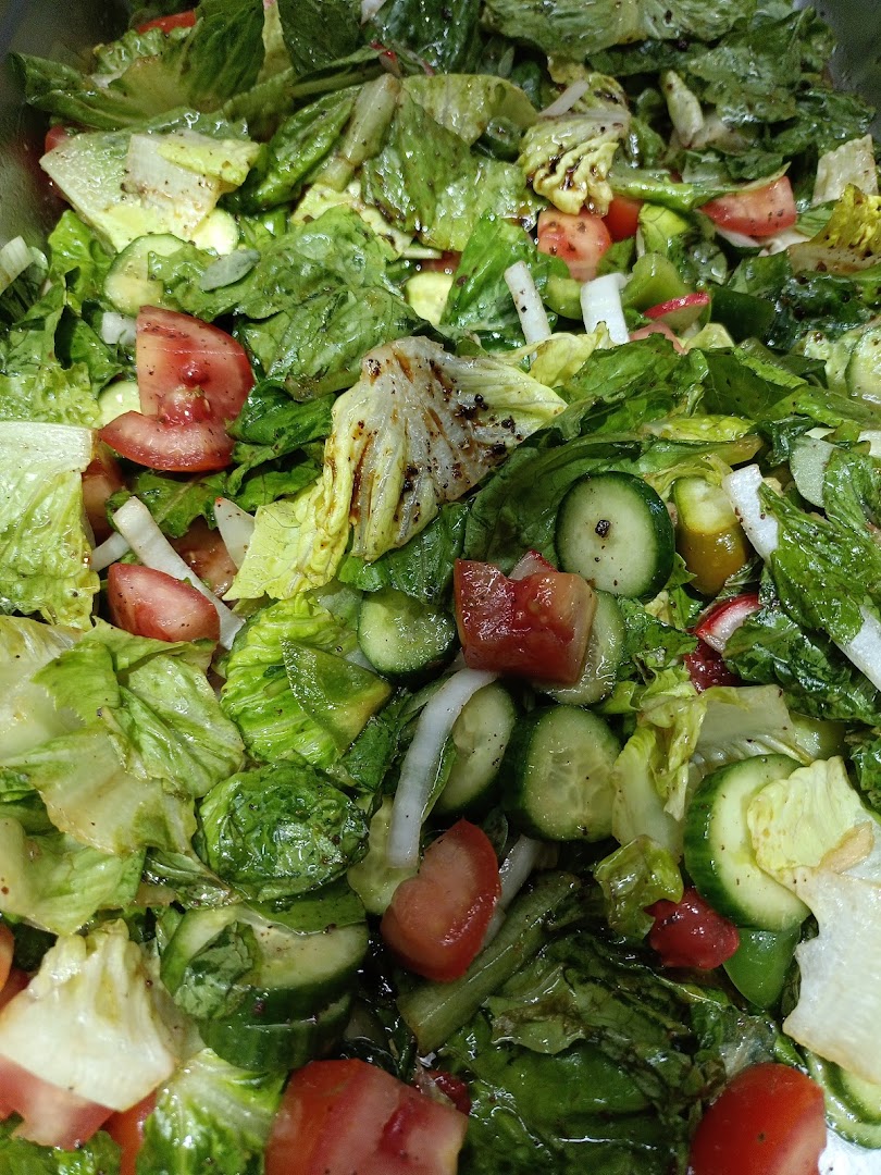A close-up view of a fresh, vibrant salad with lettuce, tomatoes, cucumbers, and onions.