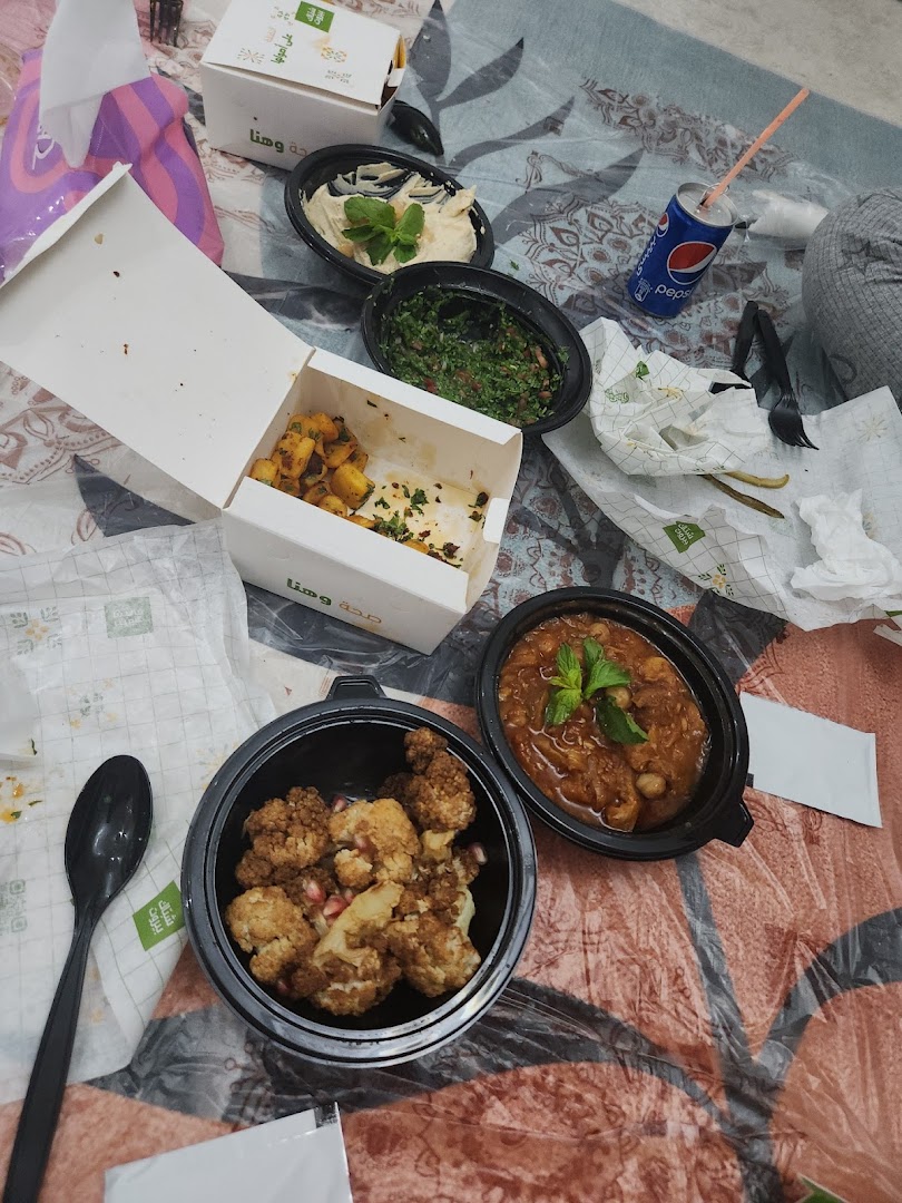 A spread of Lebanese food, including hummus, tabbouleh, cauliflower, and a chickpea dish, with a Pepsi.