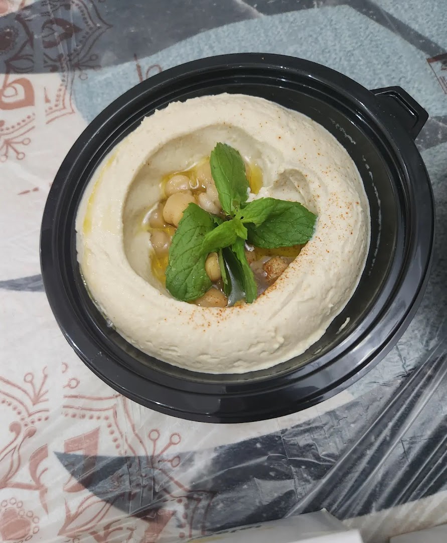 A close-up shot of a delicious serving of hummus topped with chickpeas, mint, and olive oil.