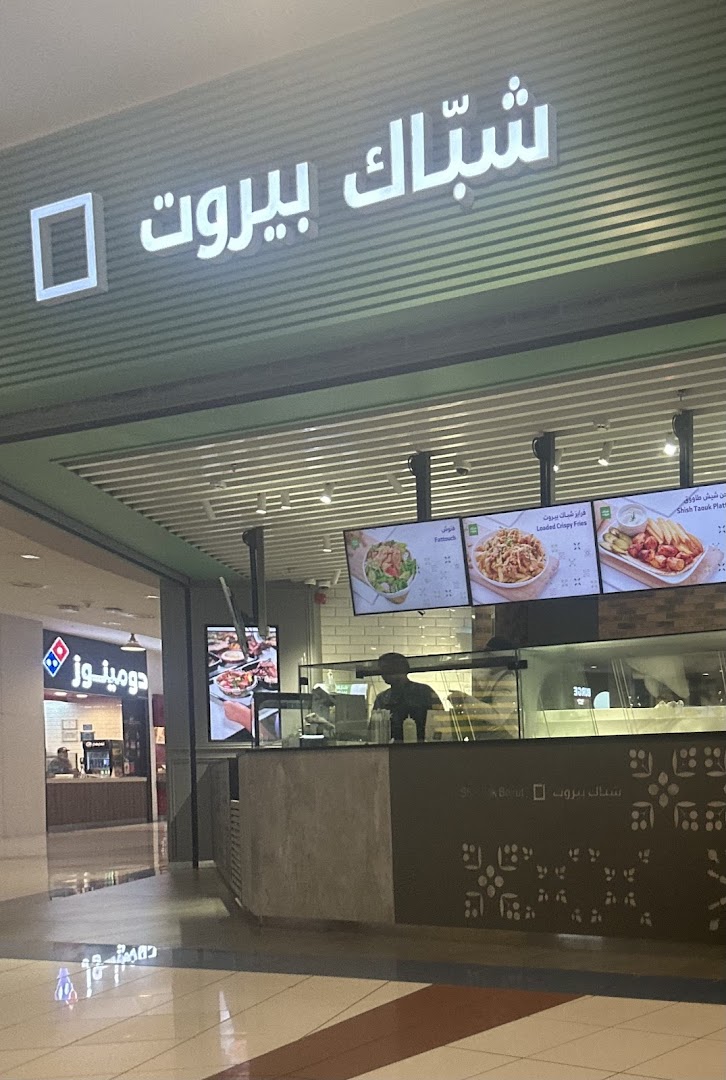The exterior of a fast-casual restaurant with a prominent sign and digital menu boards.