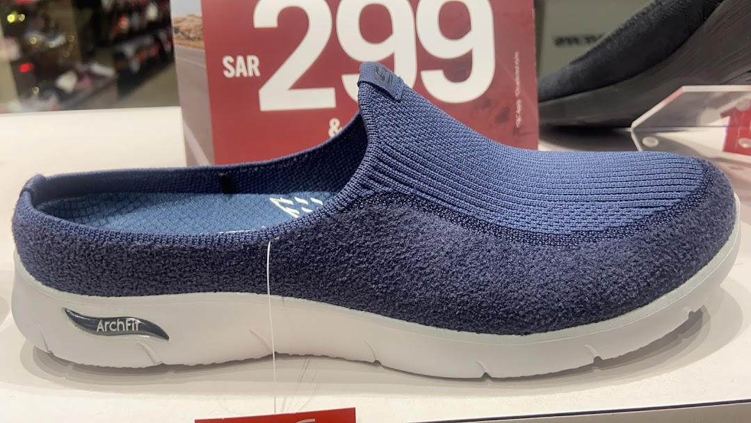 A close-up view of a blue Skechers Arch Fit slip-on shoe with a price tag in the background.