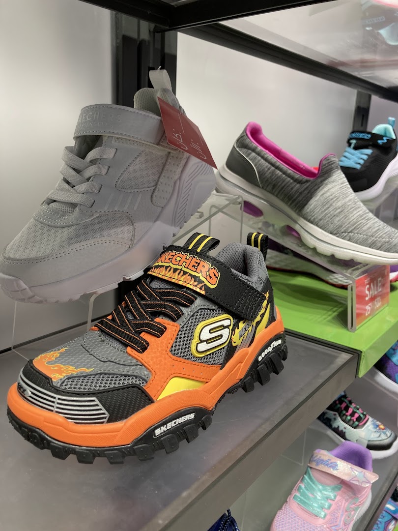 A display of various Skechers shoes, including children's sneakers and adult slip-ons.